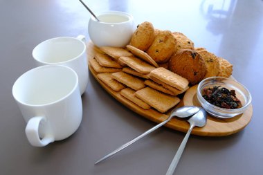A tasty snack two cups of black tea and a plate of oatmeal cookies a wooden board on the gray background, leaf tea
