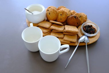 A tasty snack two cups of black tea and a plate of oatmeal cookies a wooden board on the gray background, leaf tea