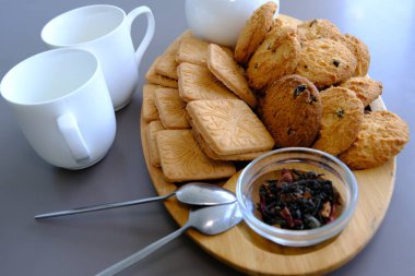 A tasty snack two cups of black tea and a plate of oatmeal cookies a wooden board on the gray background, leaf tea