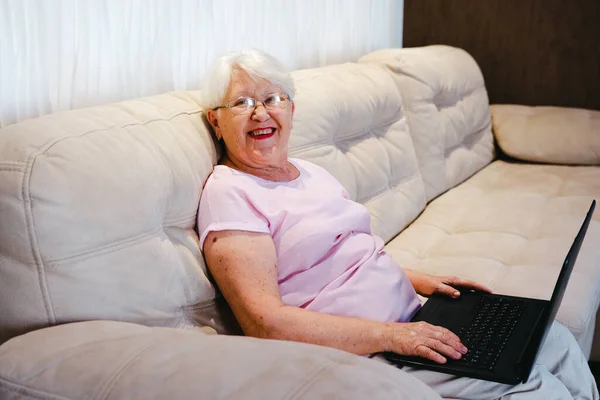 happy elderly woman using laptop computer at home. Senior mature older woman watching business training, online webinar on laptop computer remote working or social distance learning from home. 60s businesswoman video conference calling in virtual cha