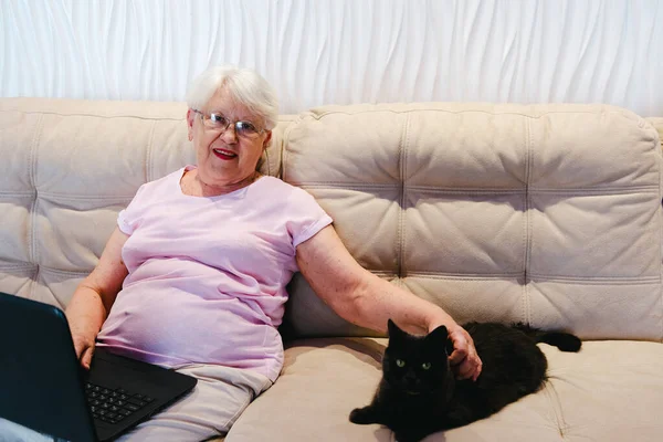happy elderly woman using laptop computer at home. Senior mature older woman watching business training, online webinar on laptop computer remote working or social distance learning from home. 60s