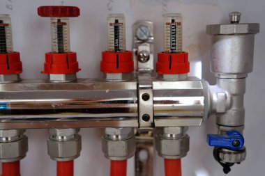 Heating system manifold valves for heat flooring and water supply in a country house. Pipes collector in a building under construction.