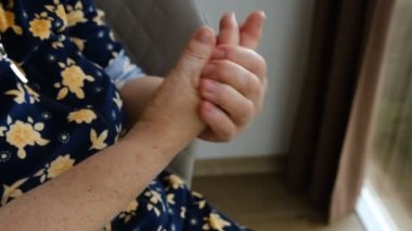 Close up of senior woman hands using white cosmetic cream and massage her hands.