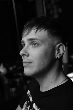 Gri arka planda izole edilmiş, yeni saç stiliyle genç bir adamın yan görüntüsü. Bir müşterinin berber fotoğrafı. Saç kesiminden sonra beyaz ve siyah renkte..