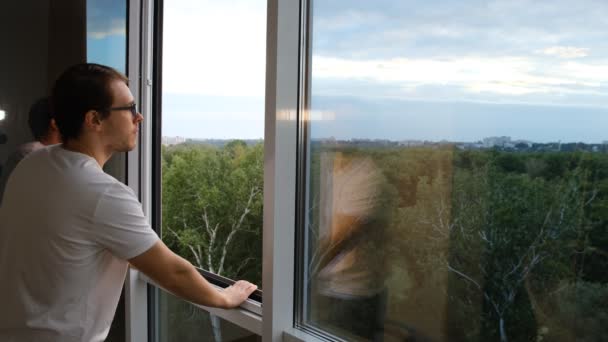 窓からの新鮮な空気 外の空気を呼吸する男の開口窓のサイドビュー 息をするハンサムな若い男オープンウィンドウ — ストック動画