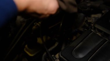 Ev servisi araba konsepti: Bir erkek motor yağı seviyesini kontrol eder ve arabanın temel bakımının lekelerini görür.