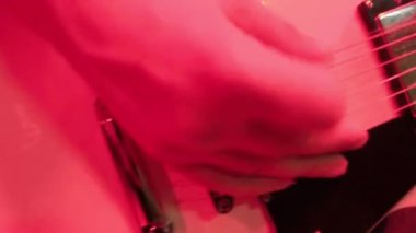 Rock müzik grubunun tekrarı. Kırmızı ışıkta elektro gitaristin kesilmiş görüntüsü.