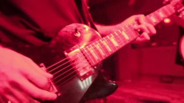 Rock müzik grubunun tekrarı. Kırmızı ışıkta elektro gitaristin kesilmiş görüntüsü.