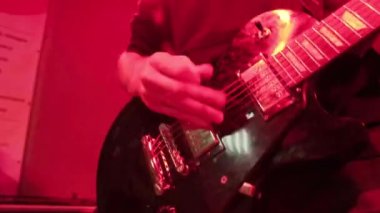 Rock müzik grubunun tekrarı. Kırmızı ışıkta elektro gitaristin kesilmiş görüntüsü.
