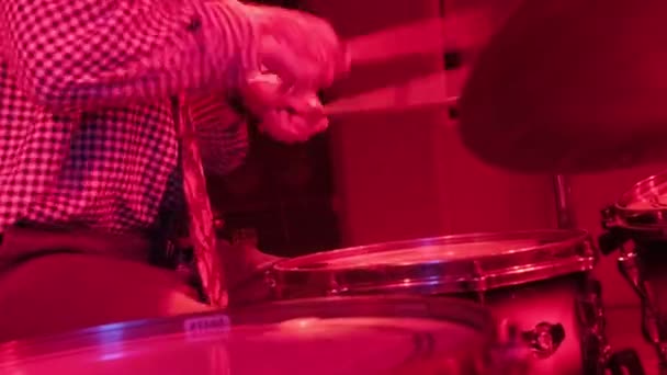ロックコンサートの前にドラムを練習するドラマー 男のレコーディング音楽上のドラムセットでスタジオで赤の光 — ストック動画