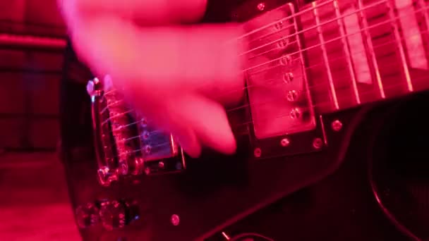 ロック ミュージック バンドの再結成 赤い光の中でのエレキギタープレーヤーのトリミングされた画像 — ストック動画