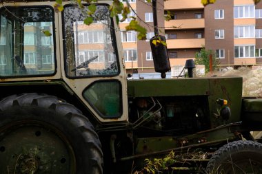 Eski traktör yeşil rengine sahip yeni modern bina işlemde.