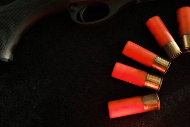 Siyah arka planda bir tüfeğin tetikleyicisi. Üzerinde siyah bir yüzey üzerinde Shotgun fişekleri olan kırmızı bir yıldırım. 12 kalibrelik pürüzsüz silahlar için mühimmat. Cephanelik avlıyorum. Koyu arkaplan