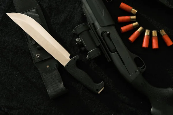 Weapon on black cloth: knife, rifle, shells,top view. Top view of knife, rifle shells