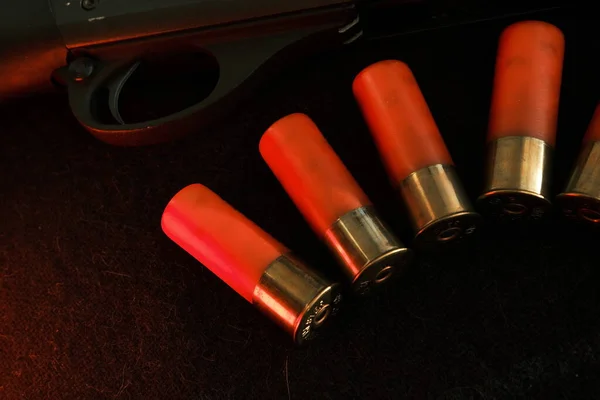 Trigger of a rifle on black background with red lightning with Shotgun shells on a black surface. Ammunition for 12 gauge smoothbore weapons. Hunting ammunition. Dark background