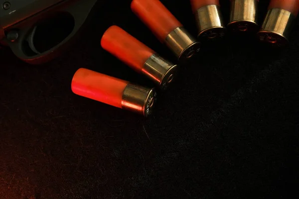 Trigger of a rifle on black background with red lightning with Shotgun shells on a black surface. Ammunition for 12 gauge smoothbore weapons. Hunting ammunition. Dark background