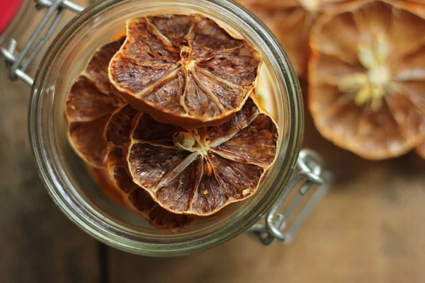 Meyve cips. Parlak turuncu koyu ahşap arka plan üzerinde bir cam kavanoza dilim kurutulmuş.