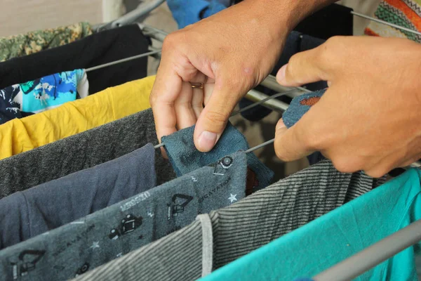 Çamaşırları kurutmak için asan bir adam. Baba ev işlerini yapar, çocuğun elbiselerini asar..