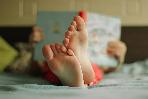 Evde eğitim. Çocuk yatakta yatarken bir kitap okur. Kitap okuma zamanı. Çocuk gelişimi. İlginç bir kitap..