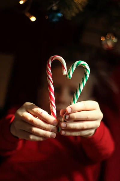 beautiful boy whith blond hair in red T-shirts lie. Cute boy with lollipop look at camera. sweet red candy on a stick. top view