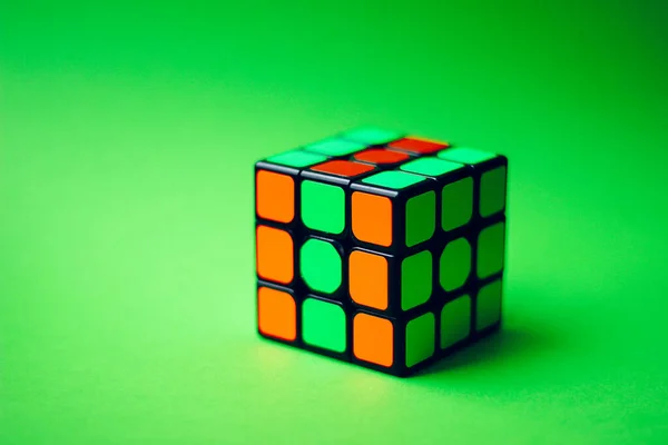 Bir masaya yerleştirilmiş Rubik küpü ve yeşil bir arka plan. Seçici odaklanma. Boşluğu kopyala.