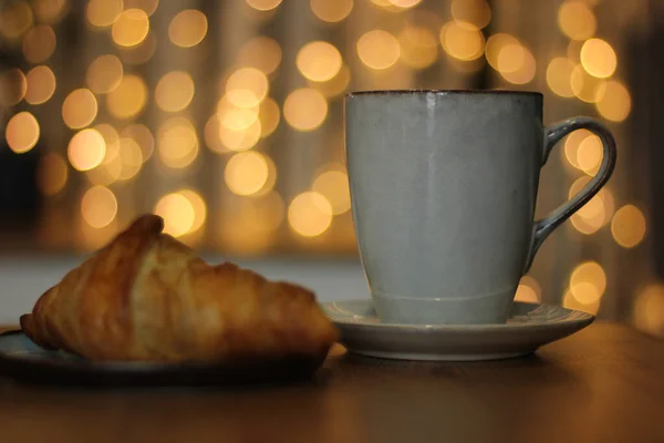 Sıcak kafedeki masada bir bardak kahve ve kruvasan.