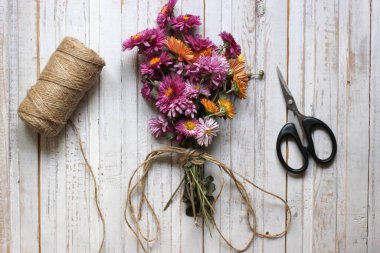 Bir buket pembe çay çiçeği, eski makas, eski ahşap tahtaların yüzeyinde ip ya da ip, üst manzara.