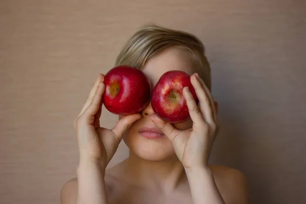 Ellerinde olgun kırmızı elmalarla küçük bir sarışının portresi. Gülümsüyor, eğleniyor. Çocuğun keyfi yerinde..