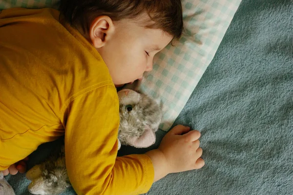 Bir çocuk bir ayıyla kucak kucak uyur.