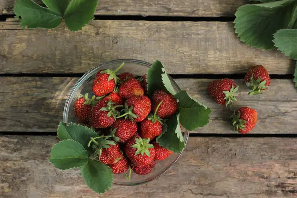 Kırsal ahşap arka plan manzaralı bir tabakta taze çilek. Ahşap masa maketinde sağlıklı yemek. Lezzetli, tatlı, sulu ve olgun arkaplanlı metin için kopya alanı.