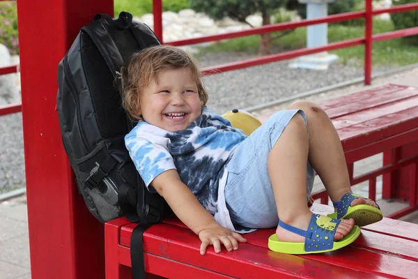 Küçük çocuk yaz mevsiminde bankta yatıyordu. Parkta bankta oturup rahatlayan tatlı bir okul çocuğu.