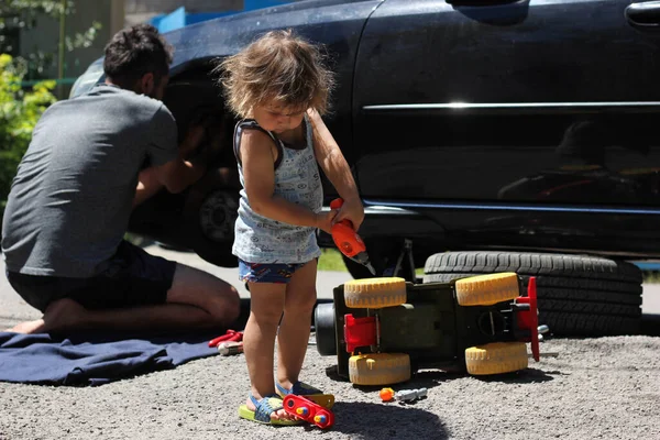 Mutlu baba ve küçük oğlu sıcak ve güneşli bir günde araba tamir ediyor ve tekerlekleri değiştiriyorlar. Baba oğluna öğretiyor..