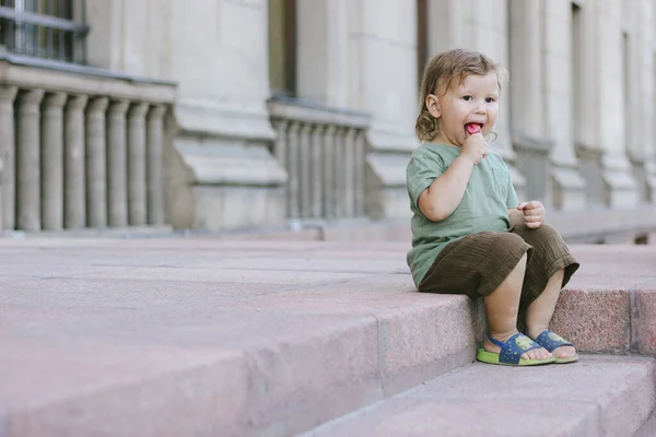 Küçük çocuk merdivenlerde lolipop yiyor. Yaz güneşli bir gün