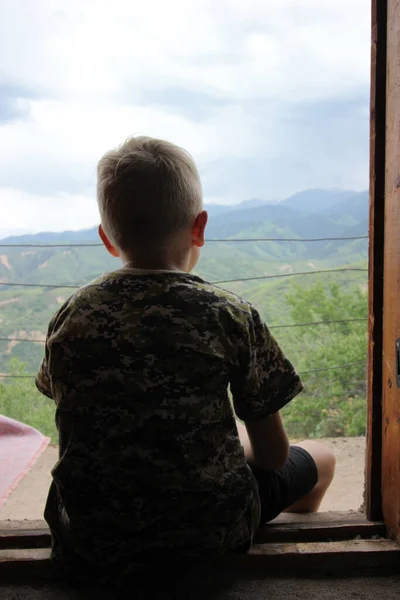 Sırtüstü dağlara bakan ilkokul çocuğu