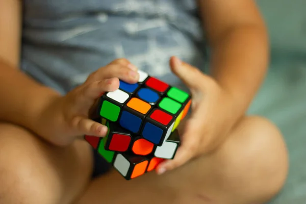 Rubik küpü çocuğun elinde, yakın plan.. Çocuk Rubik küpünü tutuyor ve onunla oynuyor..