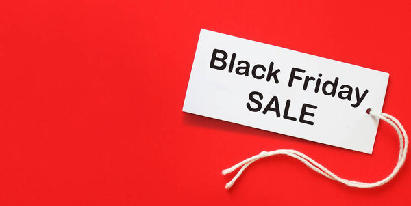 Black Friday sale. Clothing tag with inscription Black Friday on bright red background. Advertising of discounts. Copy space for text.