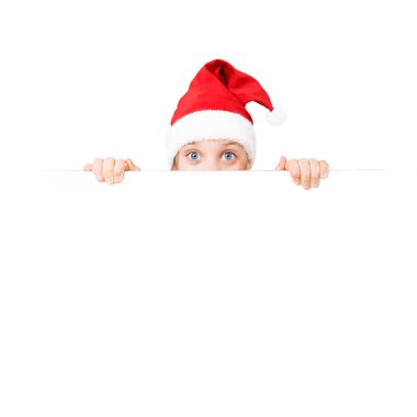 Noel Baba şapkalı mutlu kız beyaz arka planda izole bir şekilde boş bir tahtanın arkasından dışarı bakıyor. mocup. Noel ve Yeni Yıl havası. Sancak izole edildi. Noel indirimi. Noel indirimi. Beyaz bir arka planda izole edilmiş. Model