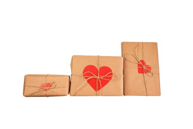 Sevgililer günü için üç hediye kraft kağıdına doldurulmuş kırmızı kağıt kalpler şeklinde kartlarla. Beyaz arka planda izole edilmiş. Sevgililer Günü için hazırlık. Çevre dostu hediye ve paket paketleri.
