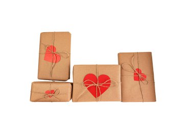 Kraft ambalaj kağıdına sarılıp kırmızı kağıt kalpler şeklinde kartpostallarla paketlenmiş dört Sevgililer Günü hediyesi. Beyaz arka planda izole edilmiş. Sevgililer Günü hazırlığı. Çevre dostu hediye ve paket paketleri.
