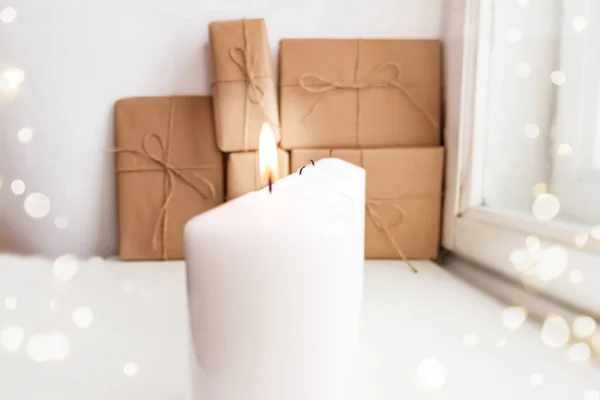 Dört mumdan biri, Noel arifesinde Advent 'in ilk haftasında, arka planda paketlenmiş hediyelerle birlikte yakılıyor. Seçici odaklanma. Odaklanamayan ışıklar. Pencerenin yanındaki mumlar. Mum ışığında Noel 'in beklentisinde. Sabah oldu.