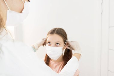 Gri arka planda şeker kutusuyla mavi renkte tıbbi şurup. Seçici odaklanma. İçinde ilaç şişesi olan bir çocuk için mavi sıvı ilaç bulunan ağız şırıngası masa arkasında duruyor. Çocukların dozaj formları. 