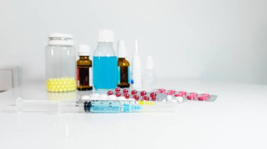 Enjeksiyon şırıngaları, tıbbi şuruplar, çeşitli tabletler, damlalar ve vitaminler masanın üzerinde. Arka plan bulanık. Seçici odaklanma. Tedavi için ilaçlar. Evde tedavi için antibiyotikler.