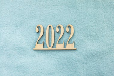 2022 numaralı ahşap, dokulu mavi kumaş arka planda yatıyor. Uzayı kopyala Seçici odaklanma. Yeni yıl kartı. Yeni Yıl Sayıları 2022.
