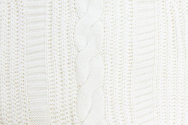 Örgü örülmüş yünlü bir süveterin beyazdaki dokusu. Seçici odaklanma. Örülmüş beyaz süveter arka plan dokusu. Süt beyazı rengi.