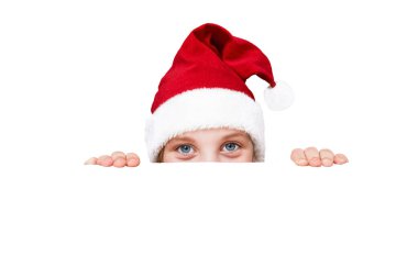 Noel şapkalı bir çocuk beyaz arka plandan dışarı bakıyor. Beyaz arka planda izole edilmiş. Ders için yer. Noel satışları ve indirimler konsepti. Noel ve Yeni Yıl için sürprizler ve hediyeler