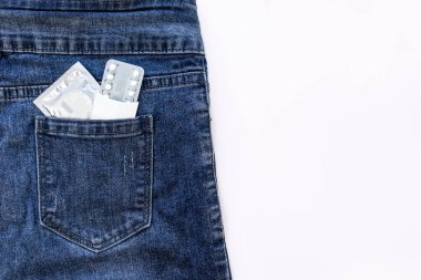 Bir paket doğum kontrol hapı ve prezervatif kot pantolonun cebinde. Kapatın. İzole edilmiş. Ergenler için cinsel eğitim kavramı. Partnerlerin doğum kontrol hapı seçimi. Aile içinde çocuk planlamak.. 