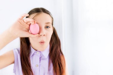 Paskalya yumurtasını gözlerinin yanında tutan çocuk şaşırır. Seçici odaklanma. Uzayı kopyala Mutlu Paskalyalar. Çocuklar ve Paskalya yumurtaları