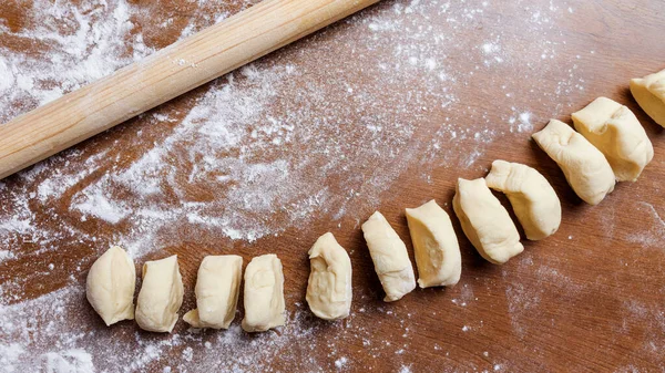 the child rolls the dough into round pieces with a wooden rolling pin. Selective focus.making dough in the kitchen. Depersonalization.
