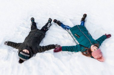children brother and sister lie in the snow and make snow angels. Selective focus.Winter fun and snow games