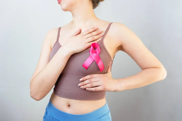 World Breast Cancer Day. prevention of breast cancer. manual examination of the breast.a woman makes a manual examination of the breast. pink ribbon as symbol of world breast cancer day.depersonalization